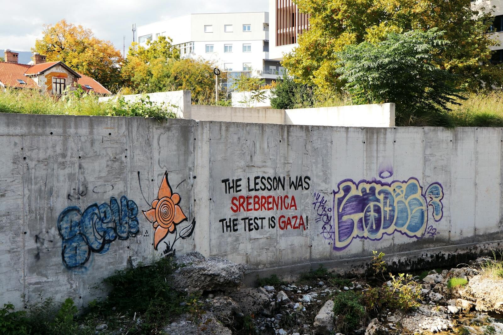 Graffiti art on a concrete wall in Mostar, Bosnia, displaying historical and cultural messages.